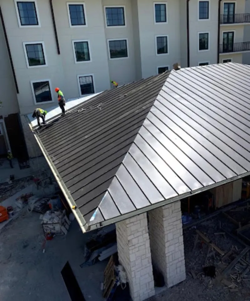 Crew installing standing seam metal roof panels on a commercial project in Leander